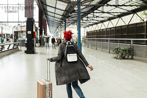 Rothaarige Frau mit Gepäck am Bahnhof