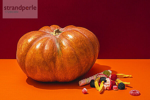 Studioaufnahme von rohem Kürbis und Halloween-Süßigkeiten