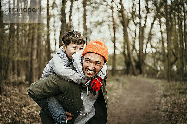 Vater nimmt seinen Sohn im Wald huckepack