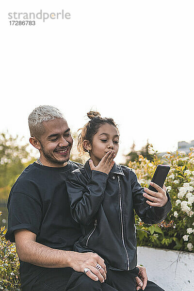 Mädchen macht Selfie mit Vater durch Smartphone im Park