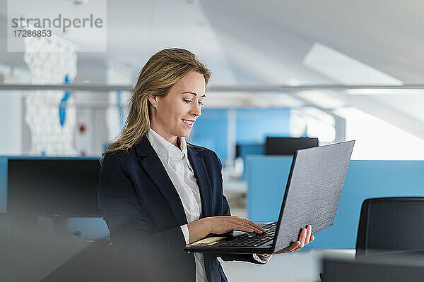 Unternehmerin arbeitet im Büro stehend am Laptop