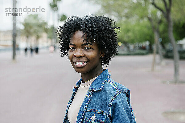 Lächelnde junge Frau mit Afrofrisur in der Stadt