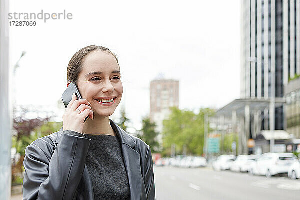Geschäftsfrau lächelnd im Gespräch am Handy in der Stadt
