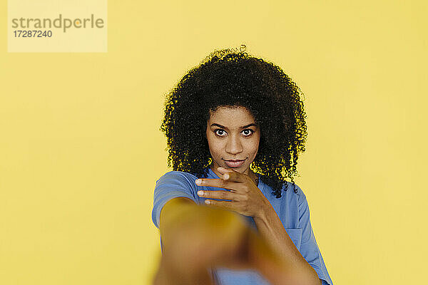 Afro-Frau  die vor einem gelben Hintergrund gestikuliert