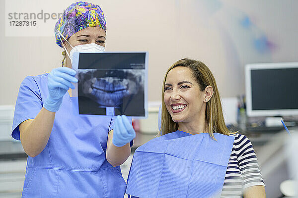 Zahnärztin zeigt einem Patienten in der Klinik ein Röntgenbild