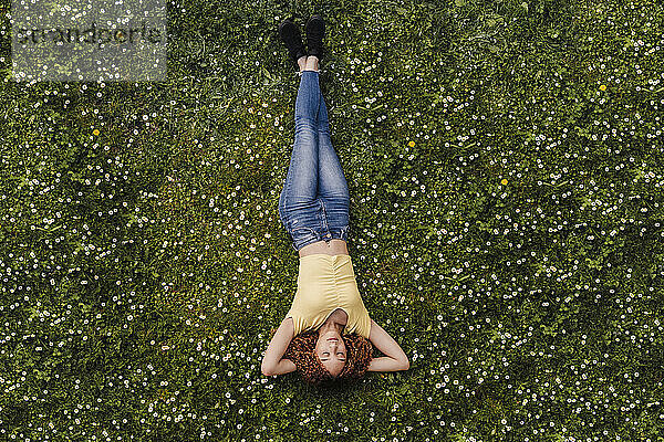 Junge Frau schläft auf einer Wiese inmitten von Blumen