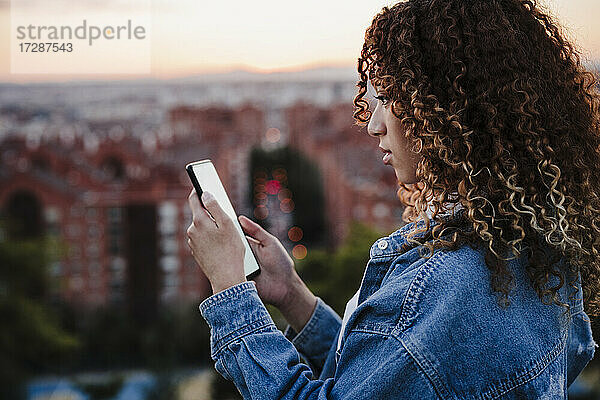 Hispanische Frau benutzt Smartphone bei Sonnenuntergang