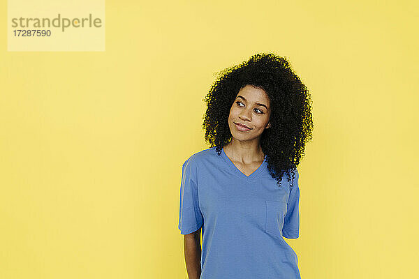 Nachdenkliche Afro-Frau vor gelbem Hintergrund