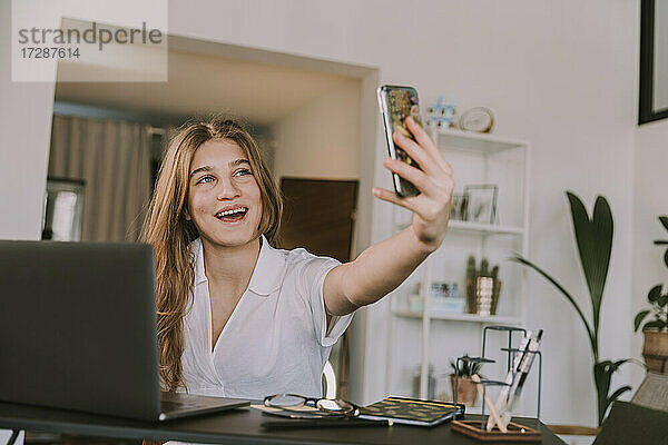 Lächelndes Mädchen  das über ein Smartphone zu Hause einen Videoanruf tätigt