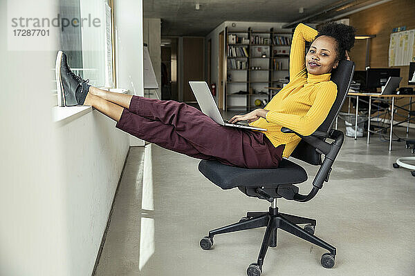 Weibliche Fachkraft mit Laptop sitzt auf einem Stuhl im Büro