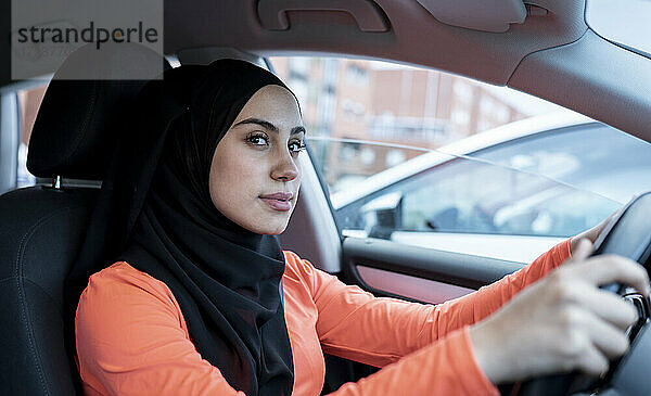 Nachdenkliche arabische Frau schaut beim Autofahren weg