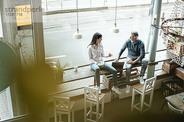 Team arbeitet zusammen  während es in einem Café am Fenster sitzt