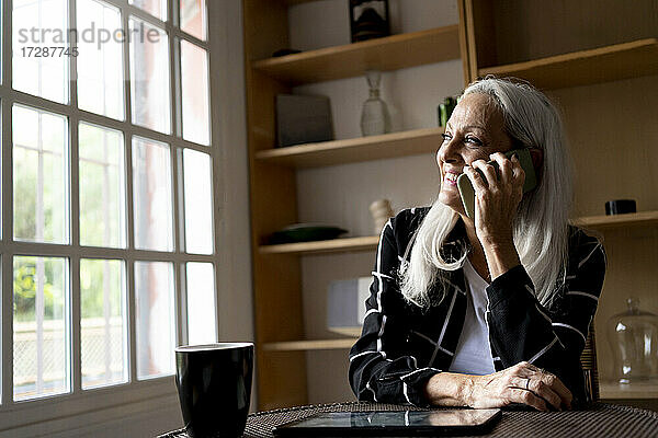 Ältere Frau telefoniert zu Hause mit ihrem Smartphone