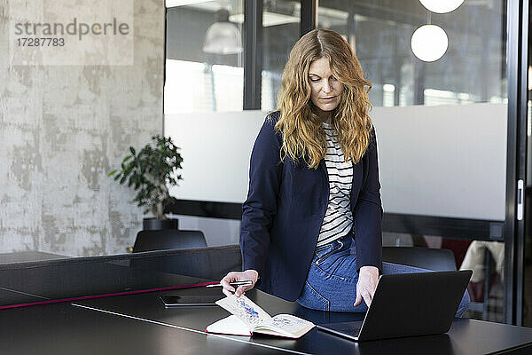 Unternehmerin mit Tagebuch und Laptop auf dem Tisch im Büro