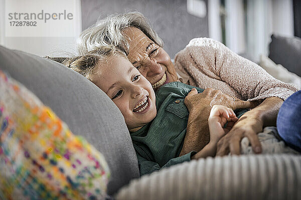 Glückliche Großmutter und Enkelin  die sich auf dem Sofa im Wohnzimmer ausruhen