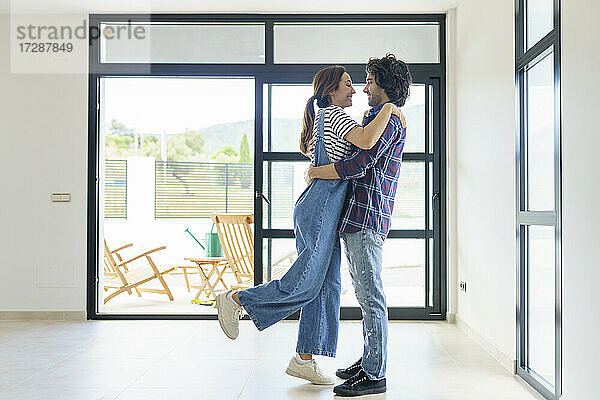 Mid adult couple embracing while relocating in new home