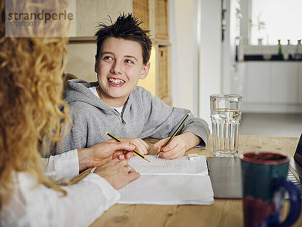 Sohn lächelt beim Lernen mit der Mutter zu Hause