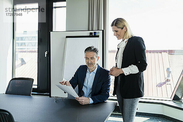 Weibliche Fachkraft  die einen Geschäftsmann ansieht  der über ein Dokument diskutiert  während er im Sitzungssaal etwas erklärt