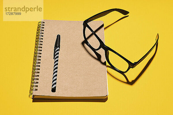 Studioaufnahme einer Brille  eines Stifts und eines Notizblocks aus recyceltem Papier