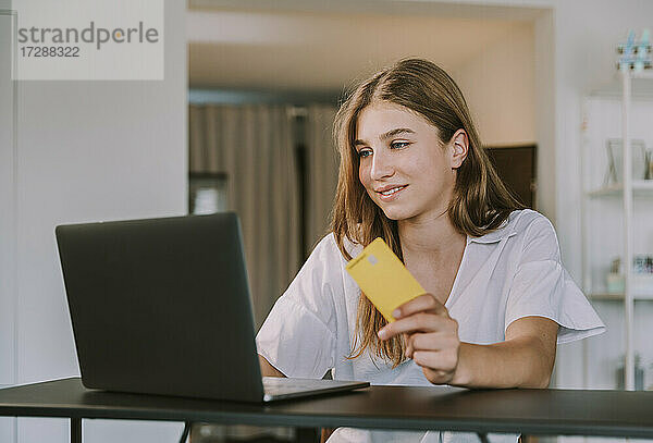 Studentin mit Kreditkarte bei der Benutzung eines Laptops zu Hause