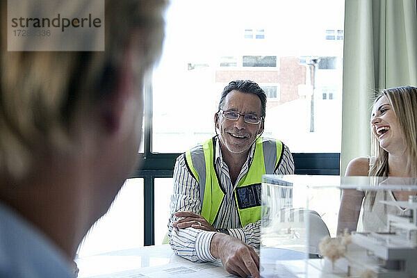 Männlicher Architekt lächelt während einer Besprechung im Büro