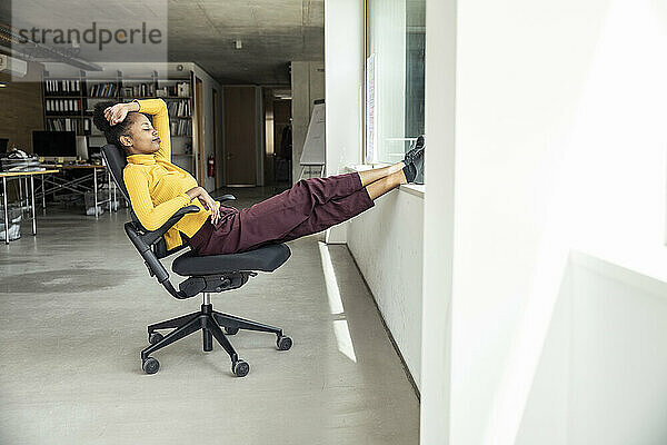 Geschäftsfrau mit hochgelegten Füßen entspannt auf einem Stuhl im Büro