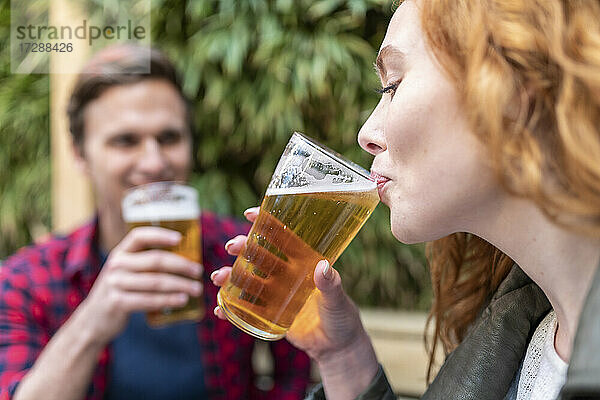 Frau trinkt Bier in einem Glas in einer Kneipe