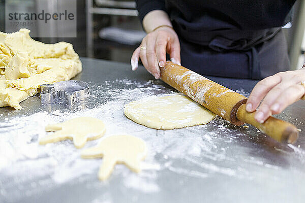 Bäckerin rollt Teig in einer Bäckerei