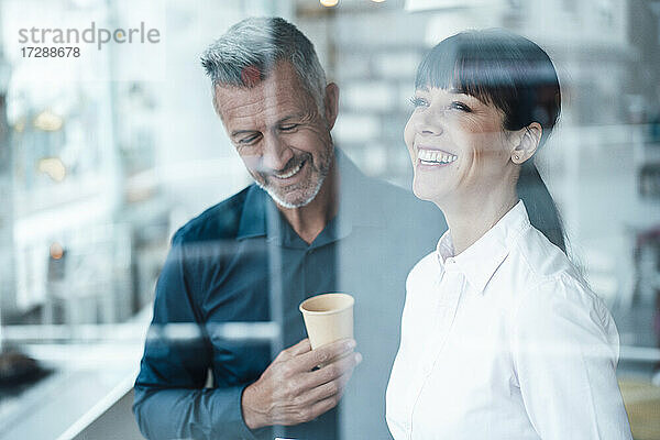 Lächelnde männliche und weibliche Unternehmer  die in einem Café stehen