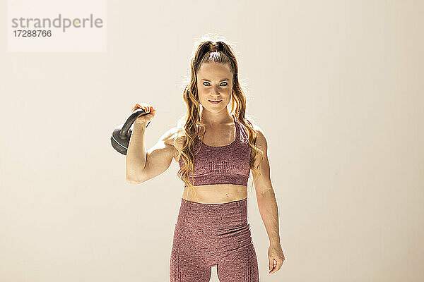 Frau in Sportkleidung beim Training mit einer Kettlebell im Fitnessraum
