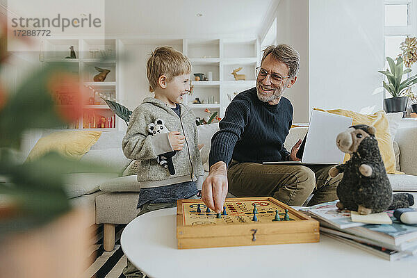 Glücklicher Vater spielt Ludo mit seinem Sohn zu Hause