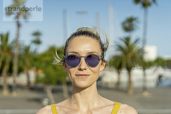 Lächelnde Frau mit Sonnenbrille an einem sonnigen Tag