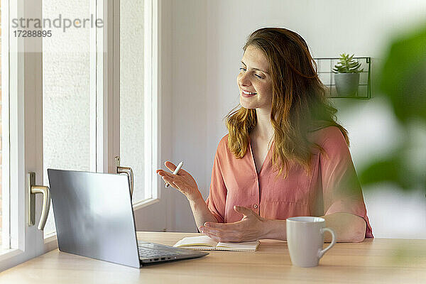 Geschäftsfrau gestikuliert während eines Videogesprächs auf dem Laptop im Heimbüro