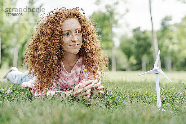 Junge rothaarige Frau liegt im Park und schaut weg