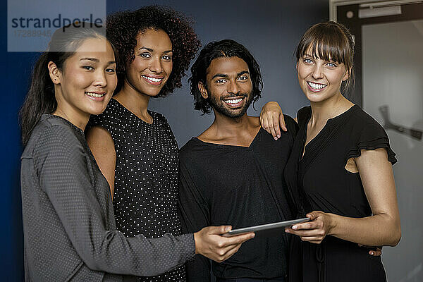 Lächelnde männliche und weibliche Fachkräfte mit digitalem Tablet während einer Besprechung im Büro