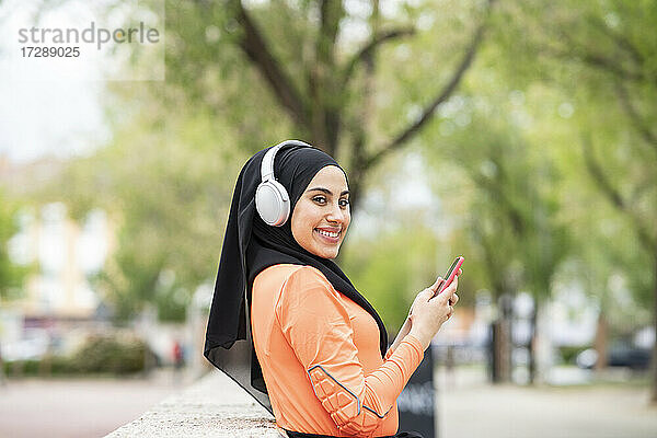 Junge Frau mit Kopfhörern und Smartphone