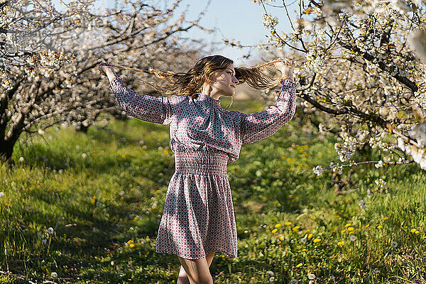 Schöne Frau kontempliert unter Kirschbäumen an einem sonnigen Tag