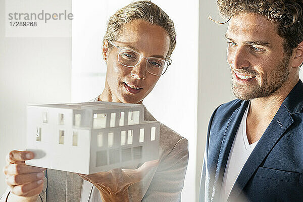 Männlicher und weiblicher Fachmann mit architektonischem Modell arbeiten zusammen im Büro