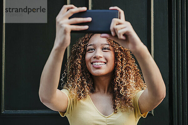 Lächelnde Frau nimmt Selfie durch Smartphone