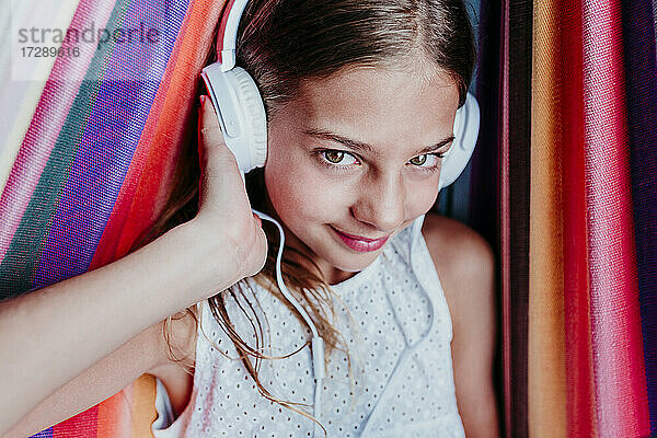 Lächelndes Mädchen genießt das Hören von Musik in der Hängematte