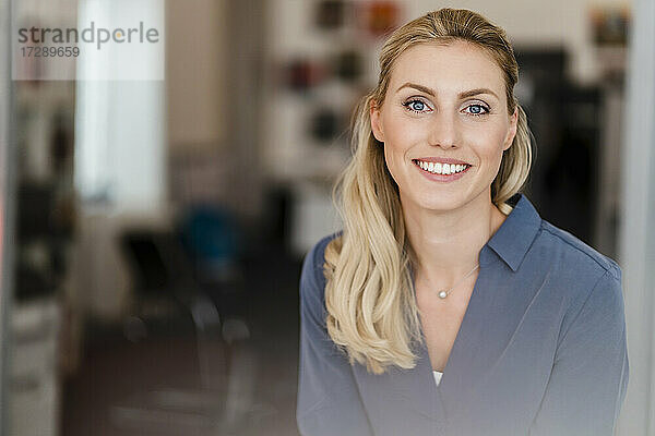 Schöne lächelnde Geschäftsfrau mit blondem Haar im Büro
