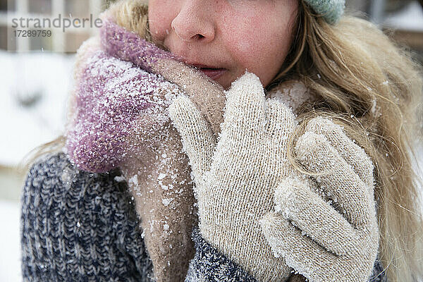 Blonde Frau mit Schal und Handschuhen bei Schnee