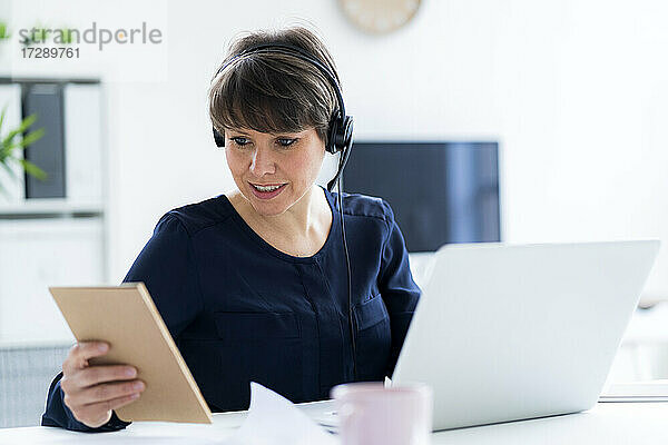Geschäftsfrau mit Headset sitzt mit Laptop am Schreibtisch im Büro