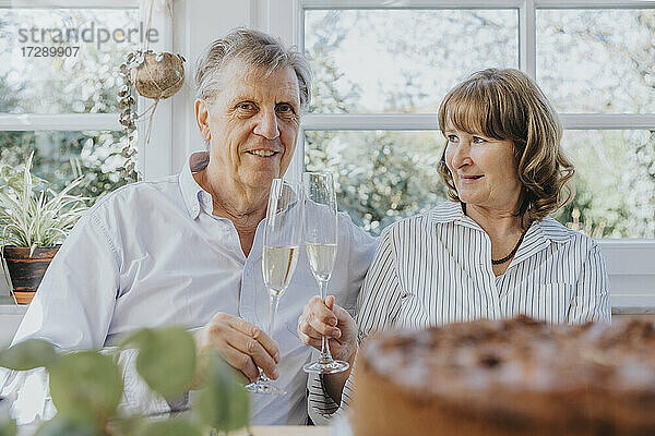Älteres Paar stößt bei einer Feier zu Hause mit Sektflöten an