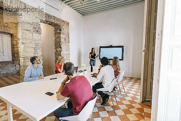 Männliche und weibliche Unternehmer sitzen im Sitzungssaal während einer Besprechung im Coworking-Büro