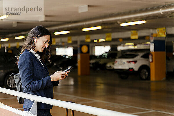 Weibliche Berufstätige  die ein Smartphone benutzen  während sie auf einem Parkplatz stehen