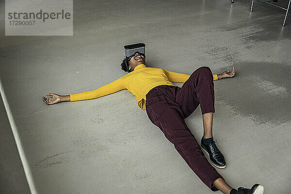 Frau mit Virtual-Reality-Headset auf dem Boden liegend im Büro
