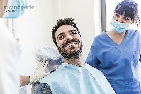 Lächelnder männlicher Patient mit weiblichen Zahnärzten in einer medizinischen Klinik