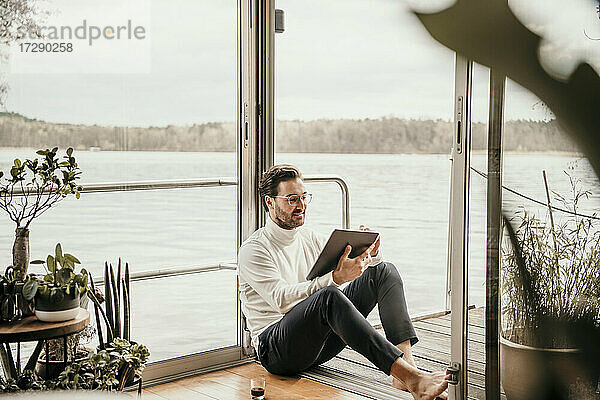Männlicher Freiberufler mit digitalem Tablet auf einem Hausboot