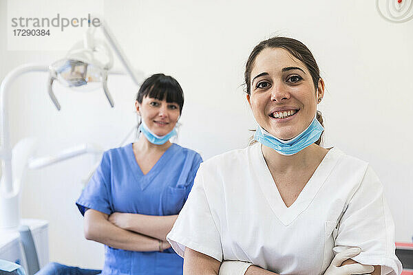 Lächelnde Zahnärztinnen mit verschränkten Armen in einer medizinischen Klinik